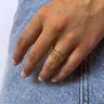 Close up view of model wearing the Wanderlust Ring which features four-layered gold ring bands, one band has circular clear stones, second band is gold beads, third band is covered with mini clear stones and fourth band is wavy with a singular clear stone