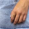 Close up view of model wearing the Forever Yours Ring which features three-layered gold ring bands, one band covered with clear stones, second band has gold beads and third band has a cross with a clear stones.