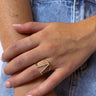 Close up view of model wearing the Sweet Dreams Ring which features two-layered gold ring bands connected with a v design with clear stones.