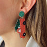 Side view of model wearing the O Christmas Tree Earrings which features an embellished red truck with a tree. 