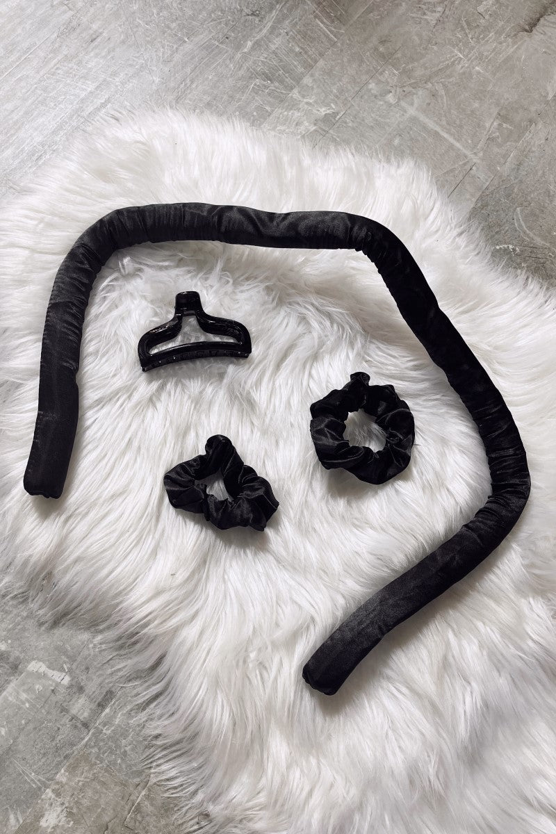 Contents of the Satin Curless Hair Set are laid out on top of white fur rug, including scrunchies, clip, and satin curler.