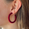 Side view of model wearing the Scarlet Velvet Hoops which features suede burgundy open hoops.