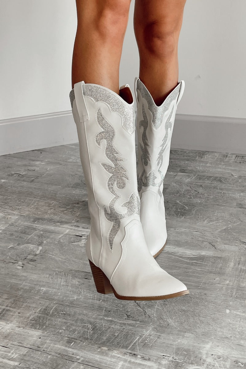 Front view of model wearing the Zane Rhinestone Cowgirl Boot in White which features a western style pattern with rhinestone details, tall boot, pull tabs, monochromatic heel and chic pointed toe.