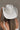 Back view of model wearing the Lainey Ivory Rhinestone String Cowgirl Hat which features cowboy shape, ivory suede fabric and rhinestone covered adjustable string.