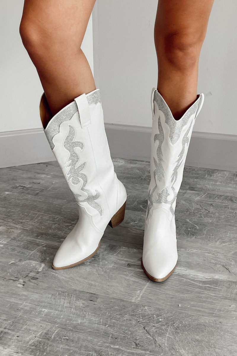 Front view of model wearing the Zane Rhinestone Cowgirl Boot in White which features a western style pattern with rhinestone details, tall boot, pull tabs, monochromatic heel and chic pointed toe.