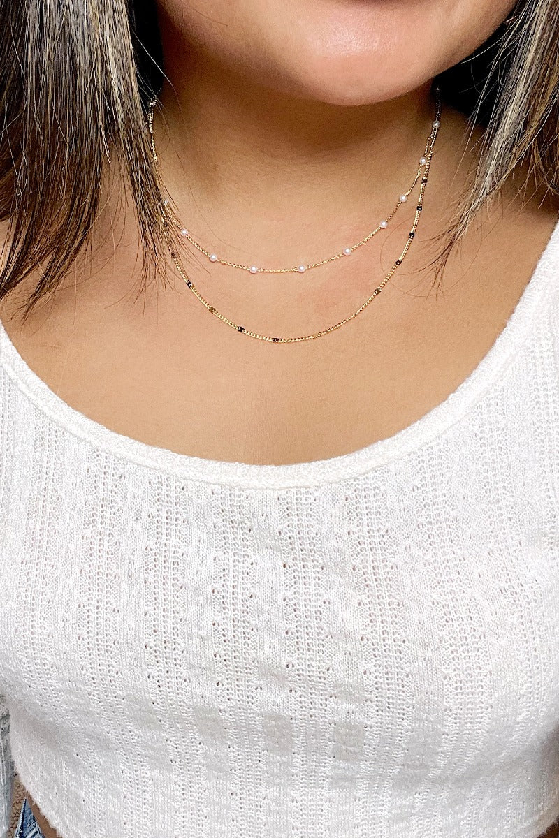 Front view of model wearing the Never In Doubt Necklace which features double-layered gold chain link with gold medallions and pearls.