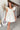 Front view of model wearing the Sweet Life Bubble Dress that features ivory satin fabric, mini length, a bubble hem, a round neckline, ruffle straps and a monochromatic back zipper with a hook closure.