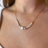 Front view of model wearing the Walk Away Necklace which features gold chain link with two-tone cream beads and large cream bead.